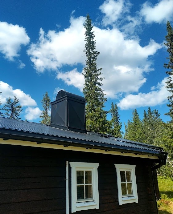 Monterad skorstenshatt på fjällstuga med berg i bakgrunden